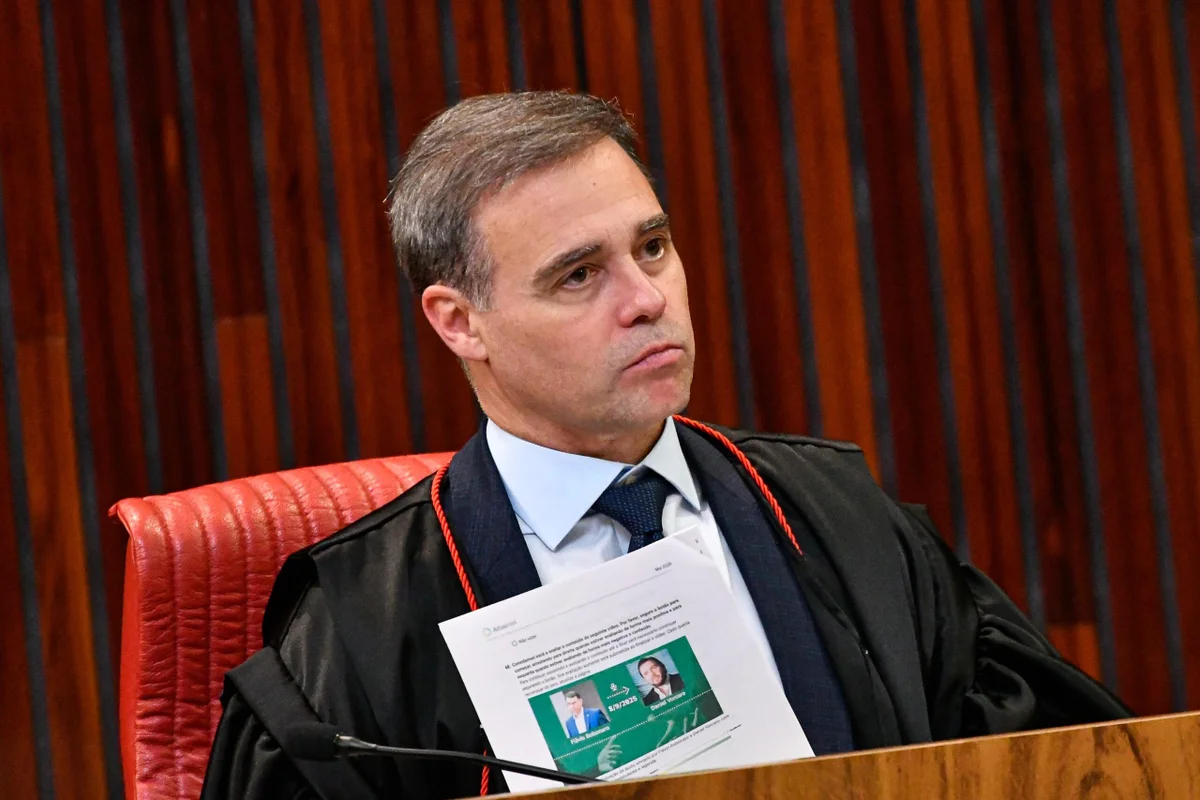 O vice-presidente do Tribunal Superior Eleitoral (TSE), André Mendonça, segura documento contendo imagens do senador Flávio Bolsonaro (PL) e do empresário Daniel Vorcaro